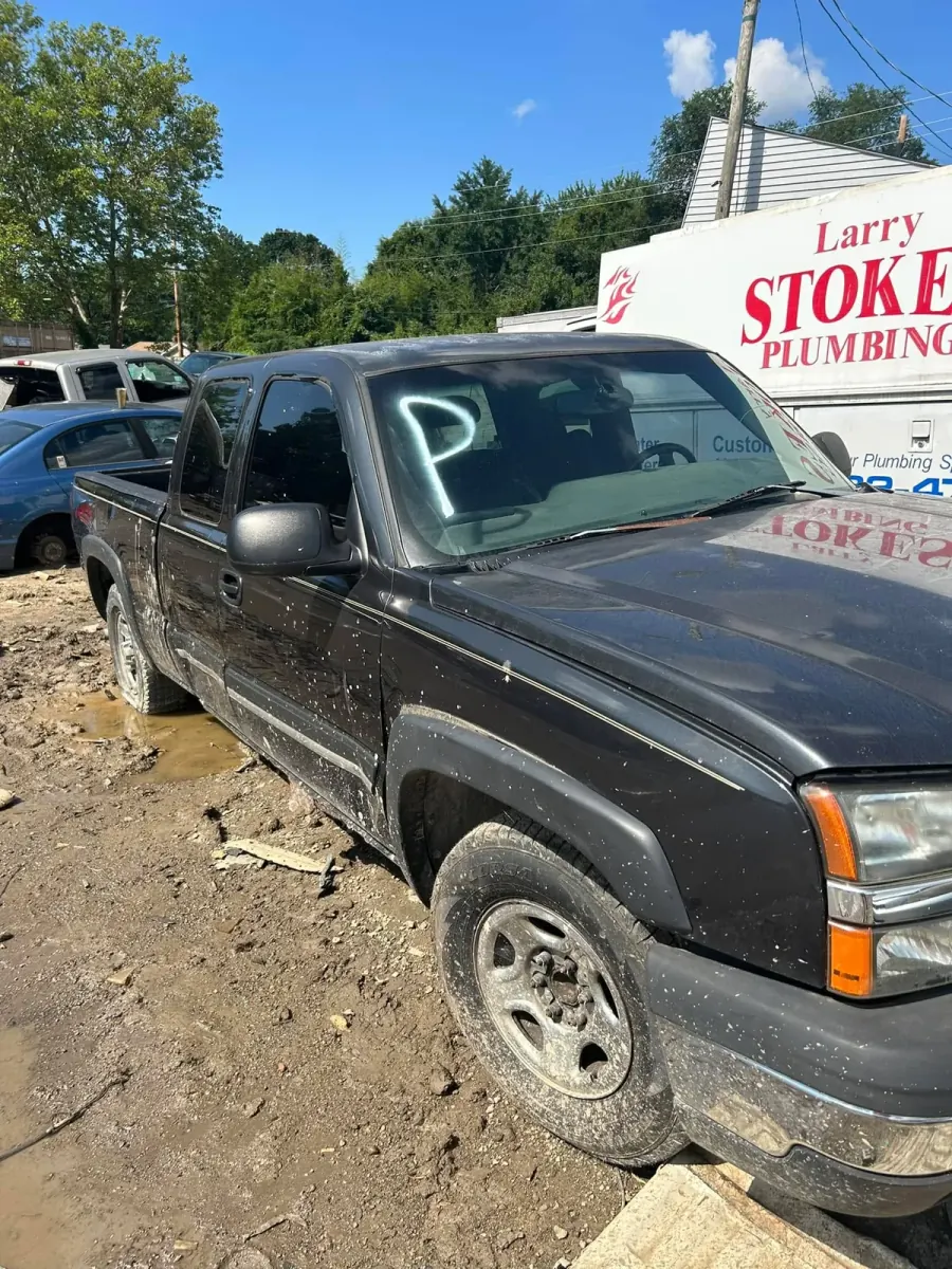 Mud-caked pickup truck marked for processing in a dirt lot -- to a scrap-only buyer, weight is the only number that matters
