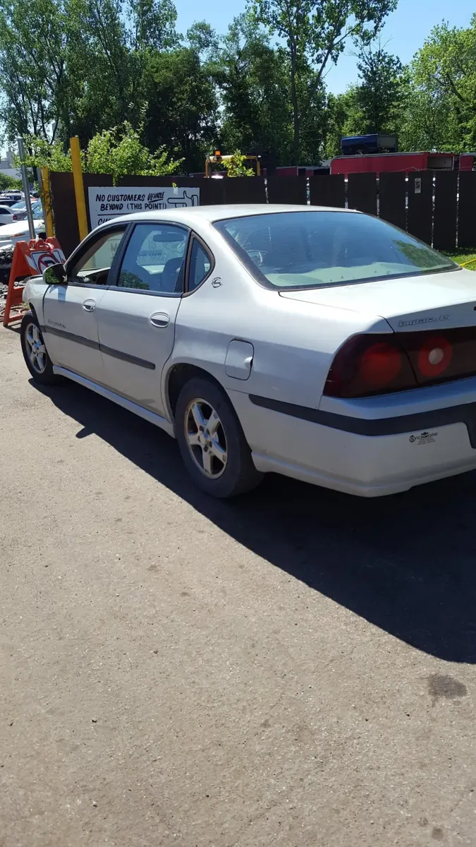 Silver sedan parked at the gate of an Indianapolis salvage yard, waiting to be signed over -- Indiana title transfers happen on the back of the title at pickup