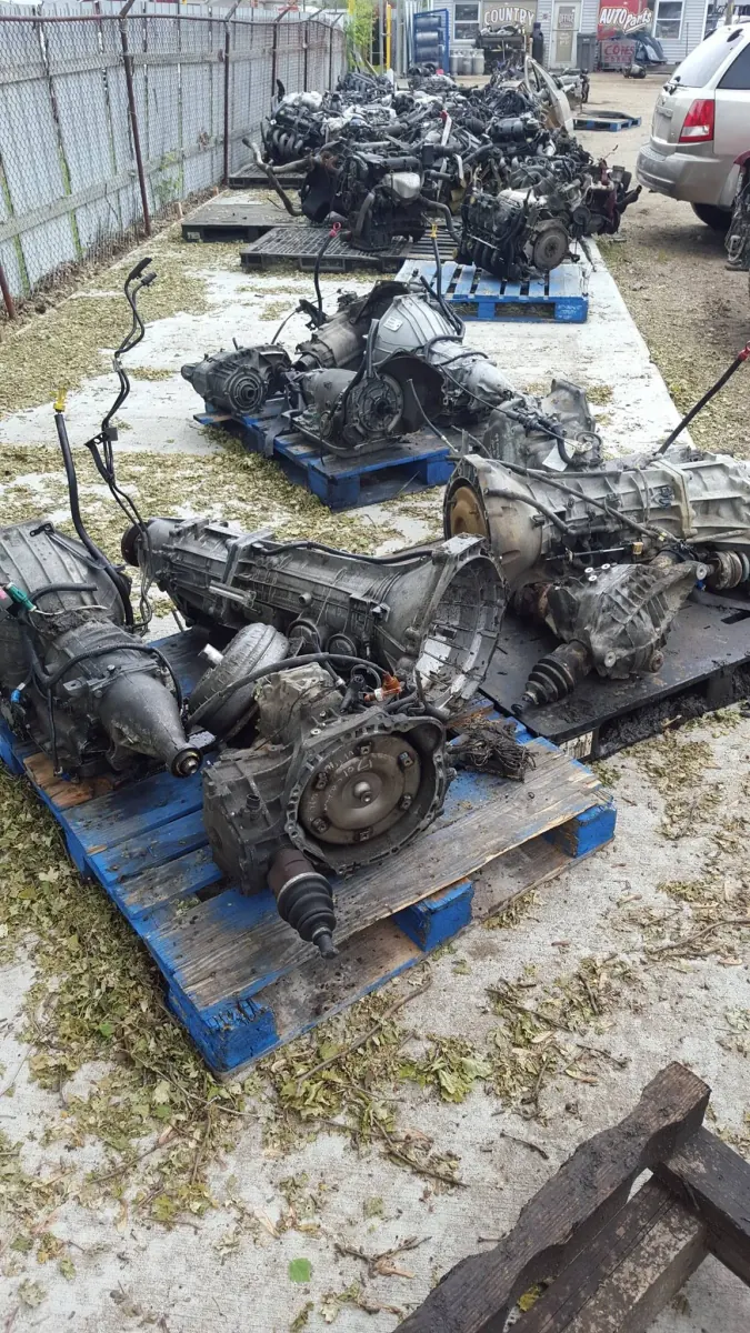 Pulled transmissions and engine cores staged on pallets beside the office at The New Country Auto Parts